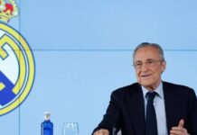 Florentino Pérez, presidente do Real Madrid, acusa Barcelona de enriquecer árbitros da LaLiga O presidente do Real Madrid de terno e gravata preta e camisa branca está à direita da foto. Ao seu lado, na parede o símbolo do Real Madrid.
