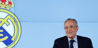 Florentino Pérez, presidente do Real Madrid, acusa Barcelona de enriquecer árbitros da LaLiga O presidente do Real Madrid de terno e gravata preta e camisa branca está à direita da foto. Ao seu lado, na parede o símbolo do Real Madrid.